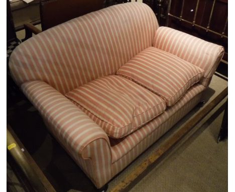 A Victorian drop-arm sofa with pink and cream striped upholstery, raised on bun feet