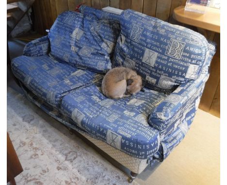 A modern two seater Wesley Barrel sofa raised on ringed and turned mahogany front legs to brass caps and castors with blue an