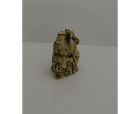 A 19th Century Japanese Meiji period carved ivory netsuke as Sennin seated on rocks, a staff at his side CONDITION REPORTS Va