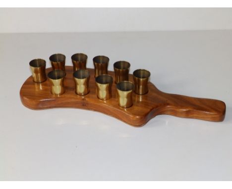 A set of brass trench art shot 'glasses' on wooden stand, each 2.25" high.