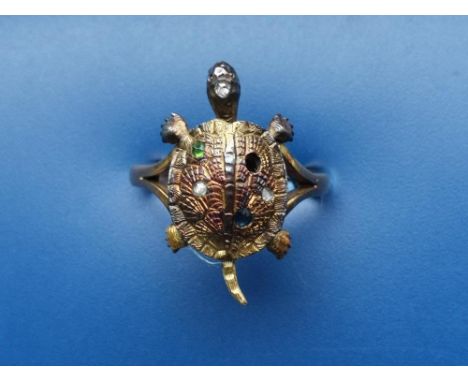 A novelty tortoise ring set with several small rose cut diamonds &amp; emeralds (one missing), having articulated head &amp; 