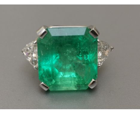 An emerald &amp; diamond three stone ring, the large rectangular cut emerald weighing in excess of 17 carats, four-claw set b