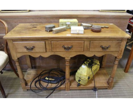 A pine dresser with three inline drawers, over pot shelf base