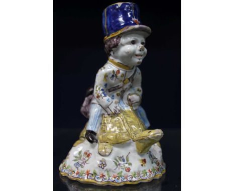 A French faience hand bell, modelled in the form of a postman riding a tortoise, polychrome hand painted in the Quimper style