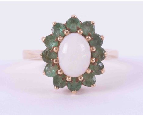 A 9ct yellow gold cluster ring set with a cabochon cut oval white opal, approx. 8.4mm x 6.4mm, surrounded by small round cut 