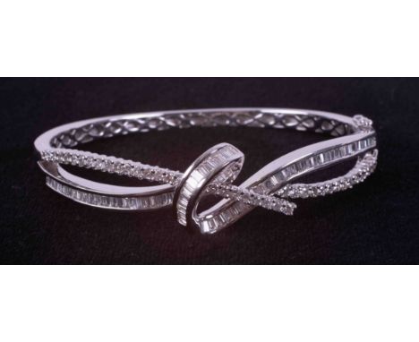An 18ct white gold knot design bangle set with a mixture of baguette cut, tapered baguette cut &amp; round brilliant cut diam