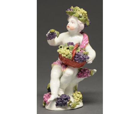 A Derby figure of a Bacchic putto, c. 1765, holding a basket of grapes, his head crowned by a conforming garland of fruit and