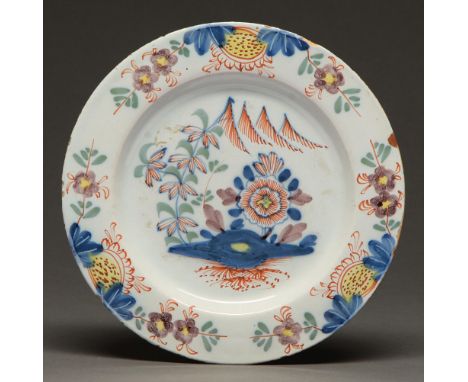 An English Delftware plate, c1770,&nbsp;painted with a flower and tree, 22.5cm diam  Rim chips, not cracked