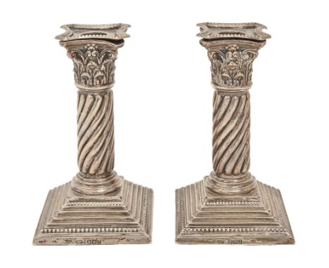 A pair of Victorian silver dwarf candlesticks, with Corinthian capital and spirally reeded shaft, on stepped square foot, noz