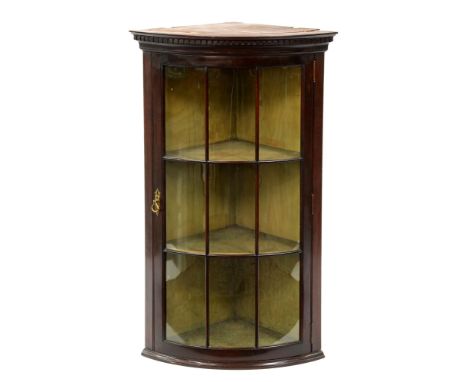 A bow fronted mahogany hanging corner cabinet, early 20th c, with dentil cornice and glazed nine pane door, key, 102cm h; 43 