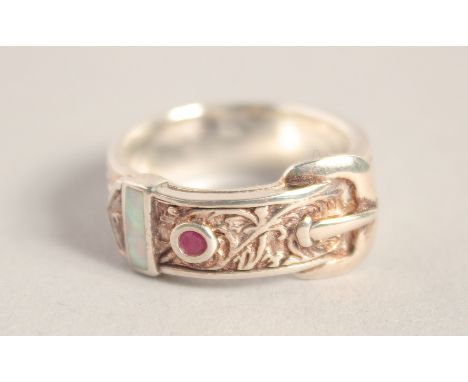 A SILVER OPAL AND RUBY BUCKLE RING.