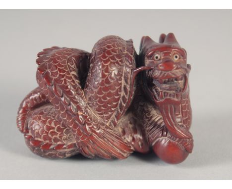 A CARVED WOOD DRAGON NETSUKE, signed. 2ins long.
