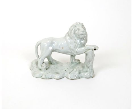 A large and rare Bow white-glazed model of a lion, c.1750-52, with head turned and resting his right forepaw on a tree stump,