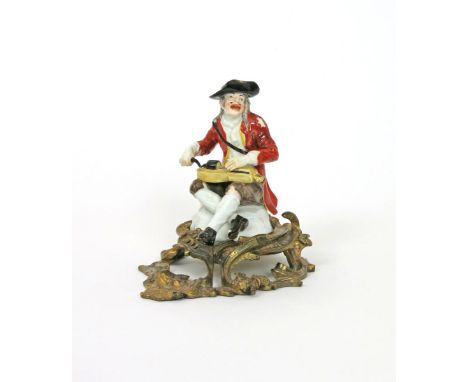 A Meissen figure of a beggar musician, c.1740, modelled by Kändler, seated and playing the hurdy-gurdy, wearing a tattered re