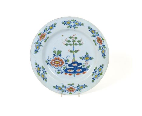 A large polychrome delftware charger, 18th century, painted with bamboo and peony issuing from holey rockwork, the rims with 