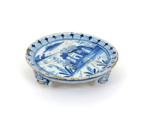 A London delftware teapot stand, c.1720, painted in blue with a small figure fishing from rocks in a river landscape, with sm