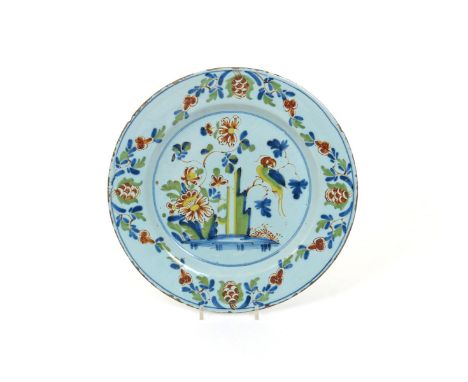 A delftware polychrome charger, 18th century, painted in a palette of blue, green, red and yellow with a long-tailed parrot p