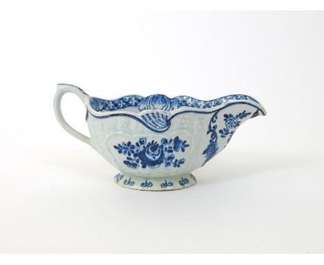 A Bow blue and white sauceboat, c.1765, painted with rose sprays within moulded floral panels, the interior rim with a formal