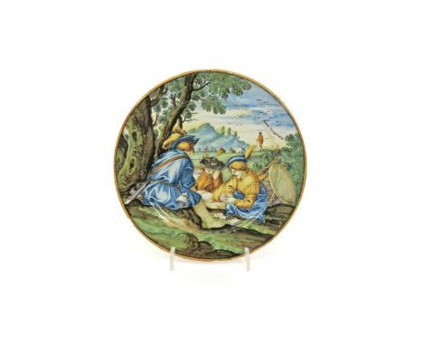 A small Castelli maiolica plate, 18th century, painted with three figures playing cards beneath a tree, with cattle and mount