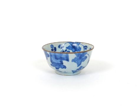 A delftware teabowl, 18th century, painted in blue with flying insects around flowering peony sprays issuing from the rim, br