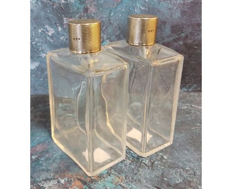 A pair of George V silver and clear glass scent flasks, the covers engine turned, 12.75cm high, Lee and Wigfall, London 1930 