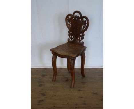 A child’s chair in the form of a hall chair with scroll carved cresting rail and flower decoration with central shield engrav