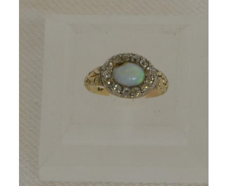 A gold coloured metal ring set with a central oval opal surrounded by a band of thirteen diamond chips (opal chipped).  Est £