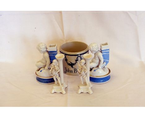 A pair of pots and covers, the lids in the form of Putto holding a bow and arrow and with quivers to their backs, a blue and 