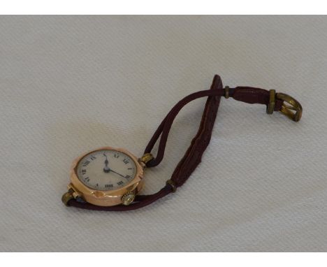 A 9ct gold cased ladies wristwatch, the engine turned dial with roman numerals and blued hands on a maroon leather strap.  Es