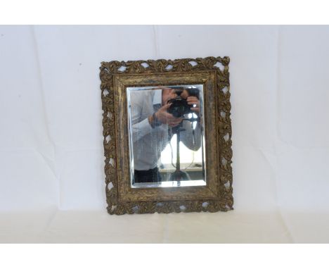 A carved and gilt framed wall mirror with bevelled glass plate.  17¾ by 14¾ins.  Est £15-30