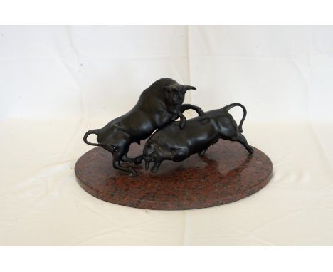 A pair of cast bronze bulls depicted in a fight, on a red and black oval marble base.  17½ins wide.  Est £150-200