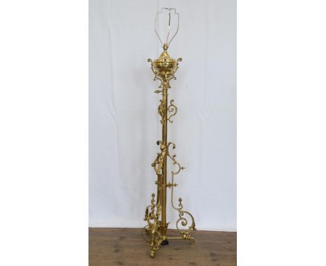 A 19th century brass oil lamp, now converted to an electric reading lamp with scroll decoration round a central stem, tripod 