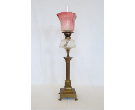 A 19th century oil lamp with ruby and clear glass shade, clear glass reservoir, Corinthian column lower section on four paw f