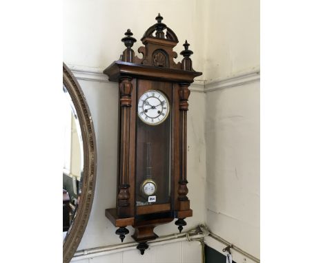 A walnut cased Vienna Regulator wall clock with turned finials to the pediment above a glazed door flanked by reeded pillars,