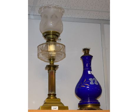 A Victorian cast brass corinthen column paraffin lamp, clear glass reservoir, etched shape, stepped plinth; another glass and