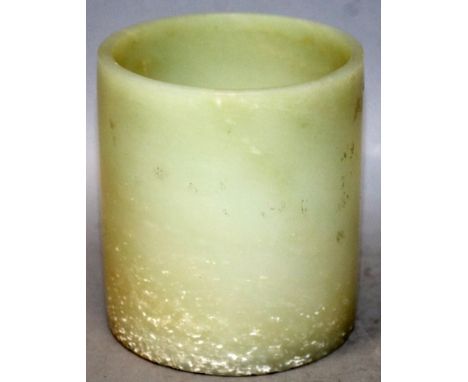 A CHINESE CELADON JADE BRUSHPOT, the stone with flecked white inclusions, the base with a Qianlong seal mark, 3.7in diameter 