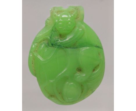 A SMALL CHINESE APPLE-GREEN JADE-LIKE CARVING, in the form of a monkey on lotus, 1.6in high x 1.25in wide.