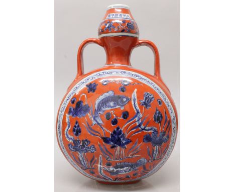 A CHINESE MING STYLE CORAL GROUND BLUE & WHITE PORCELAIN MOON FLASK, decorated to each side with a panel of a fish swimming t