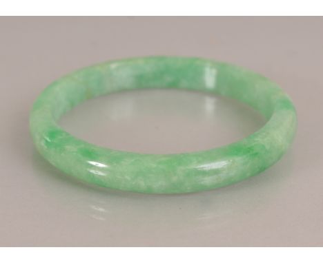 A CHINESE APPLE GREEN JADE BANGLE, with paler inclusions, 2.7in diameter, the inner rim 2.1in diameter.