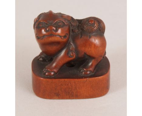A GOOD QUALITY JAPANESE MEIJI PERIOD CARVED BOXWOOD NETSUKE OF A SHI-SHI, standing with turned head on an oval plinth, 1.1in 