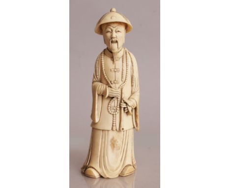 AN UNUSUAL 19TH/20TH CENTURY CHINESE IVORY CARVING OF A MANDARIN, standing in flowing robes with a court necklace about his n