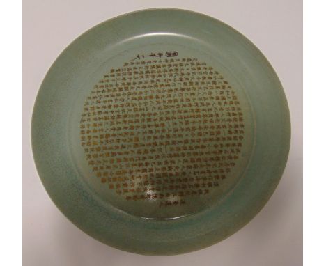 A Chinese celadon glazed dish carved with Chinese calligraphy, gilded character marks and seal to the base, 29.5cm (dia)