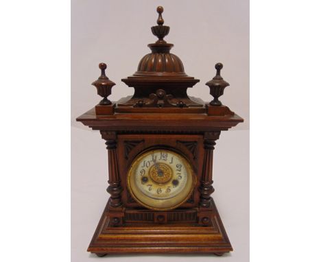 An oak cased mantle clock two train movement in architectural wooden frame, column supports and urn finials, Arabic numerals 