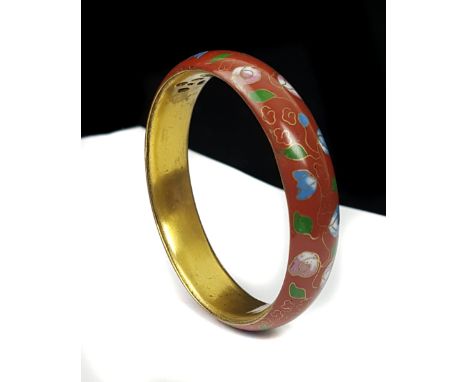 A Chinese cloisonne bangle decorated with a continuous floral garland on a claret ground, gilded interior, 7cm diam approx