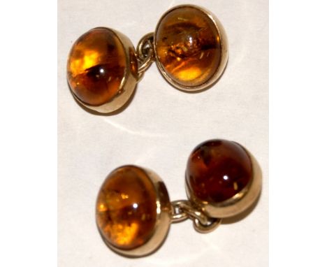 A pair of yellow metal and cabochon amber set cufflinks 