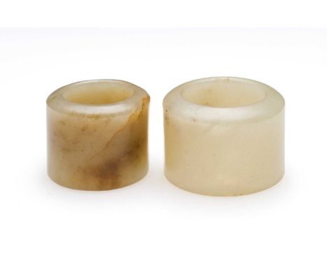 □ TWO CHINESE JADE ARCHERS RINGS, QING DYNASTY, 19TH CENTURY comprising: a pale celadon jade ring with black inclusions, 2.4c