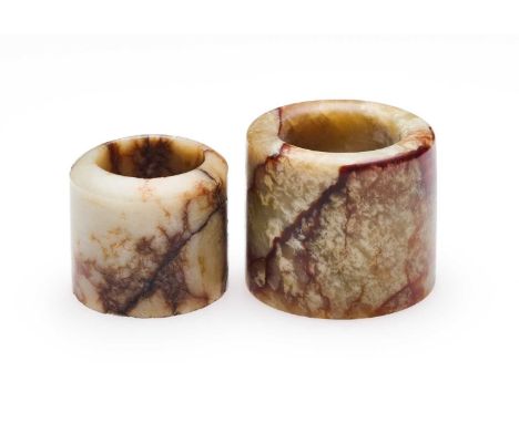 □ TWO CHINESE JADE ARCHERS RINGS, QING DYNASTY, 19TH CENTURY comprising: a cream jade ring with red veining, 2.2cm high; and 