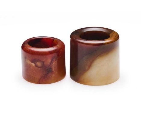 □ TWO CHINESE JADE ARCHERS RINGS, QING DYNASTY, 19TH CENTURY comprising a red and orange jade ring, 2.6cm high; and a large c
