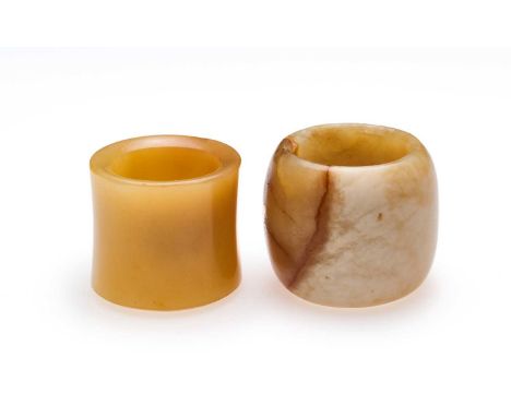 □ TWO CHINESE JADE ARCHERS RINGS, QING DYNASTY, 19TH CENTURY comprising: a celadon and cream jade barrel-shaped ring , 2.7cm 