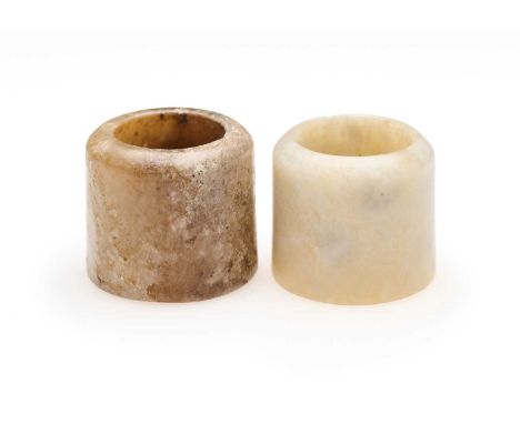 □ TWO CHINESE JADE ARCHERS RINGS, QING DYNASTY, 19TH CENTURY comprising: a celadon and cream jade ring, 2.7cm high; and a cre